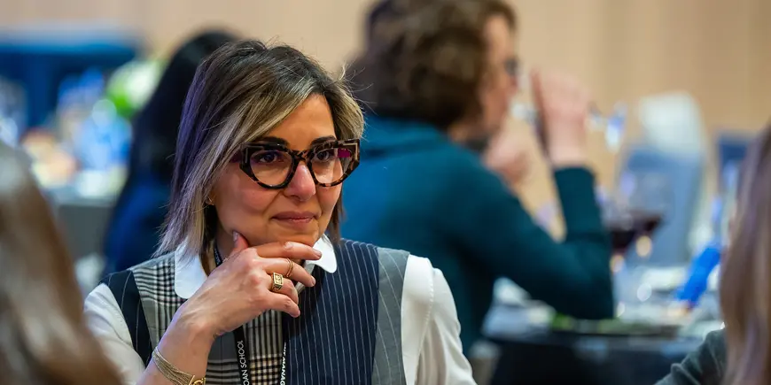 Woman in glasses sits and listens to event speaker