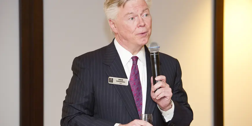 A man speaks into a microphone while holding a glass of champagne