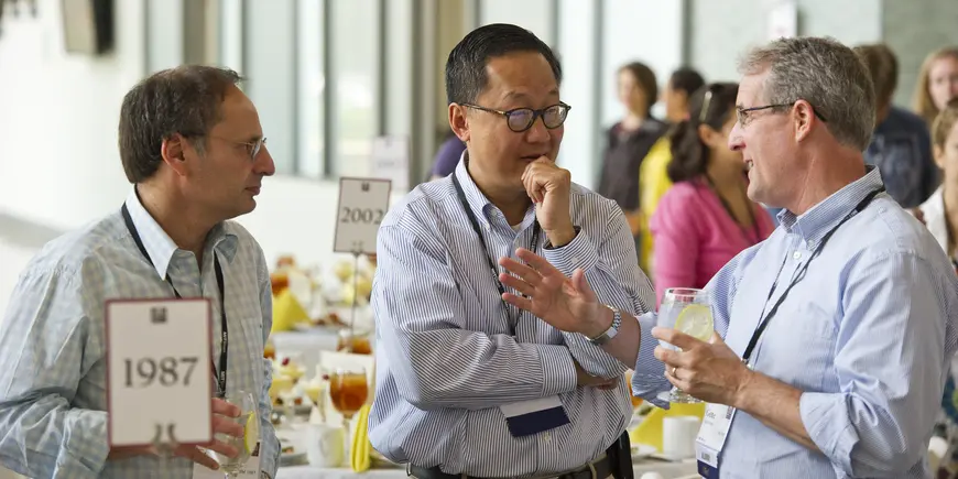Three men speak at large gathering