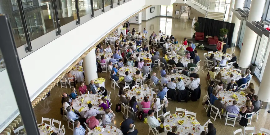 Large lobby filled with tables, at which many people are seated
