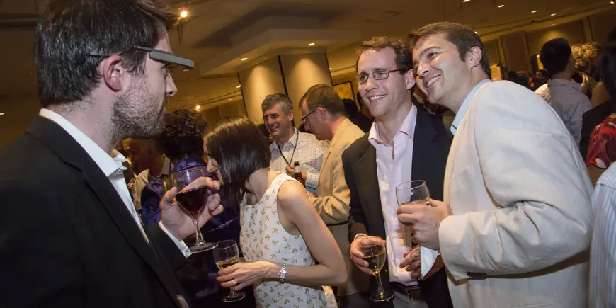 A man takes a picture of two men with a Google Glass