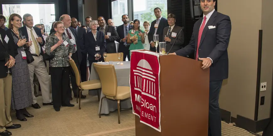 A man at a podium addresses a room of people