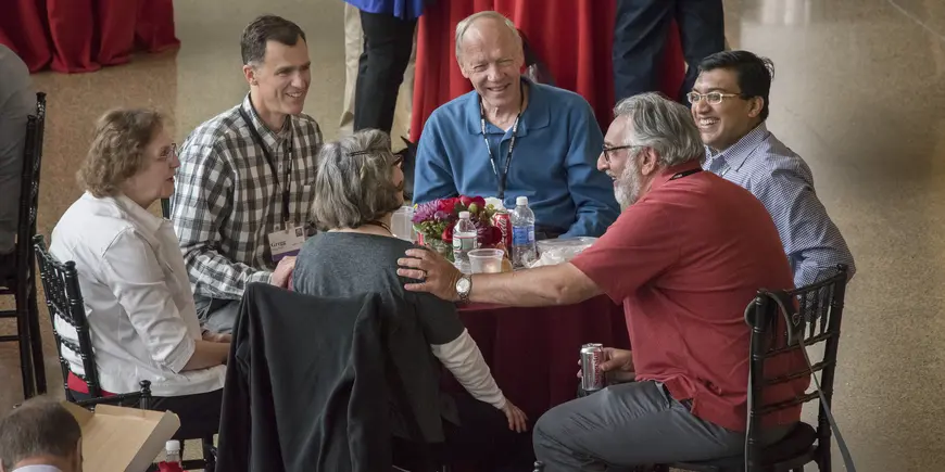 A group of people talks and laughs while sitting at a table