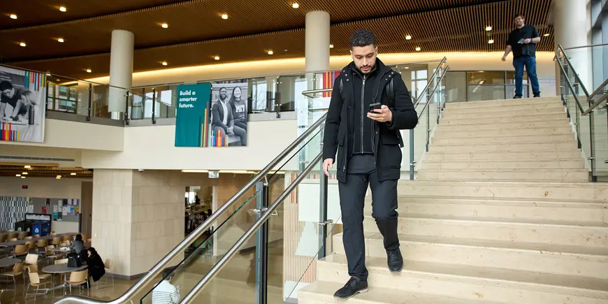 Mike Sanchez walks down the large staircase in the main MIT Sloan building