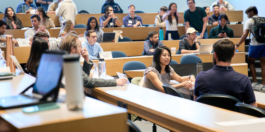 Megan Hung chats with another student in a full lecture hall.