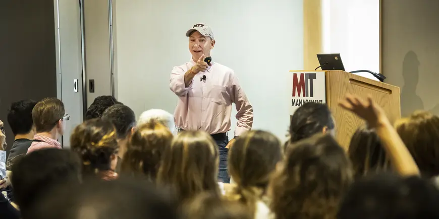 A man addresses someone with a raised hand in a large group