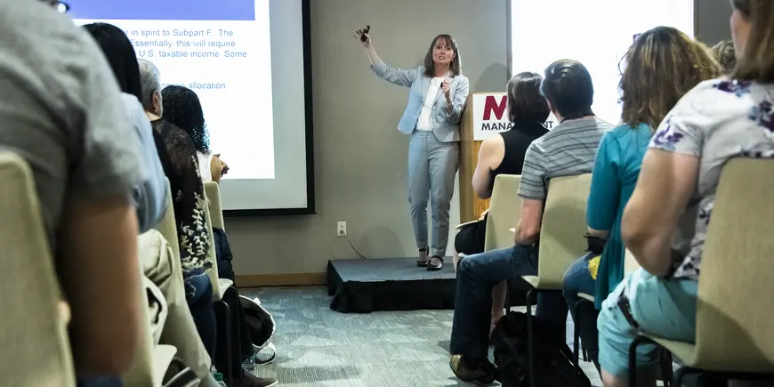 A woman speaks to a room full of people