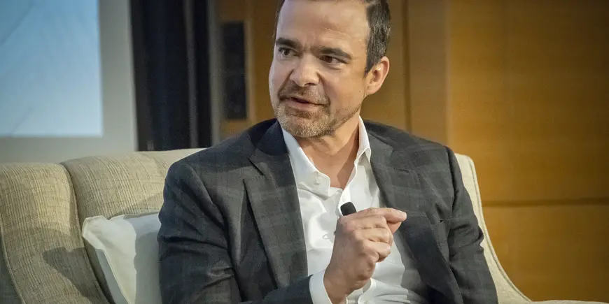 A man sitting in a chair speaks to someone off camera