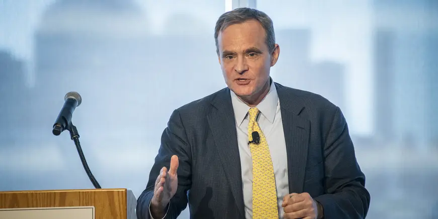 A man in a suit speaks next to a podium