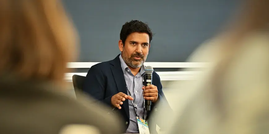 A man speaks into a microphone to an audience