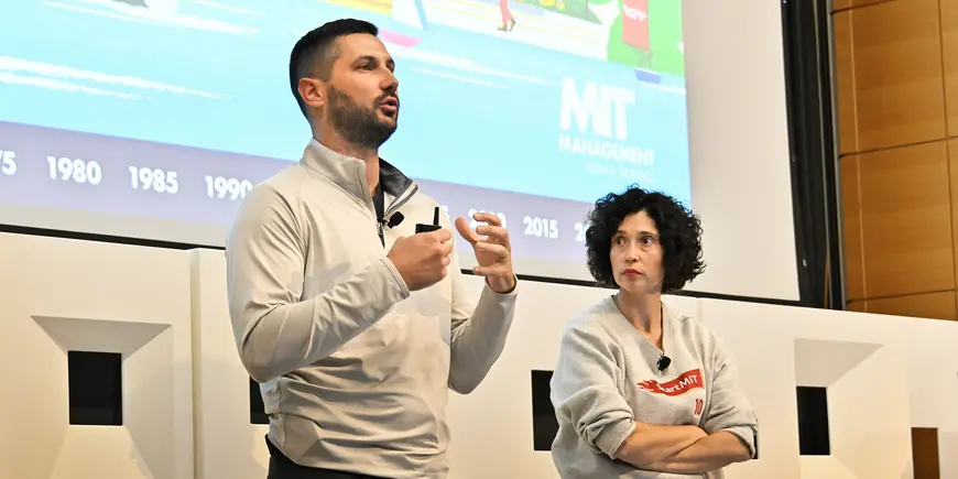 A woman listens to a man speaking to an audience