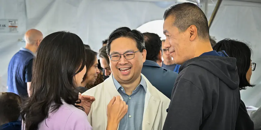 Three people laugh while speaking together