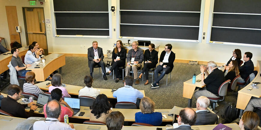 A panel of five people speaks to an audience