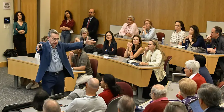 A man gesticulates while presenting to classroom