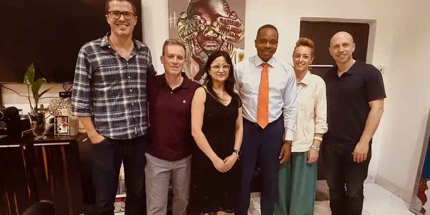 Group photo of students and host with art behind them.