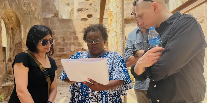 Photo of students looking at woman's notebook