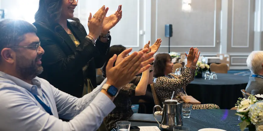 A small group of business people around a table, clapping after a workshop presentation