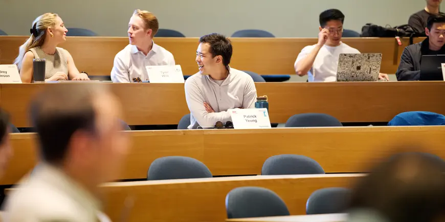 Patrick Yeung sits in an MIT Sloan lecture hall. He smiles at someone out of frame