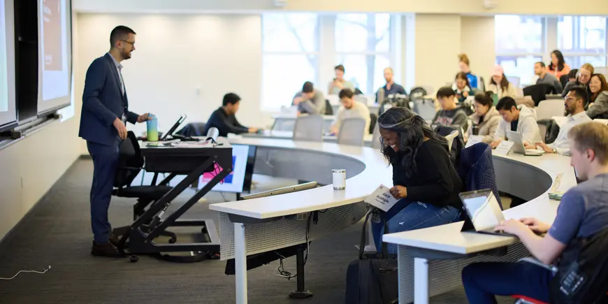 Alecia Asiamigbe sits in an MIT Sloan lecture room. She is seated in the front row, smiling, and the photo is taken from the side.