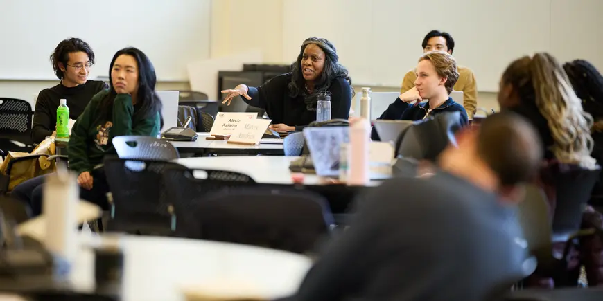 Alecia Asiamigbe sits in an MIT Sloan classroom during class. She is speaking, facing towards the front of the room while other students listen to her