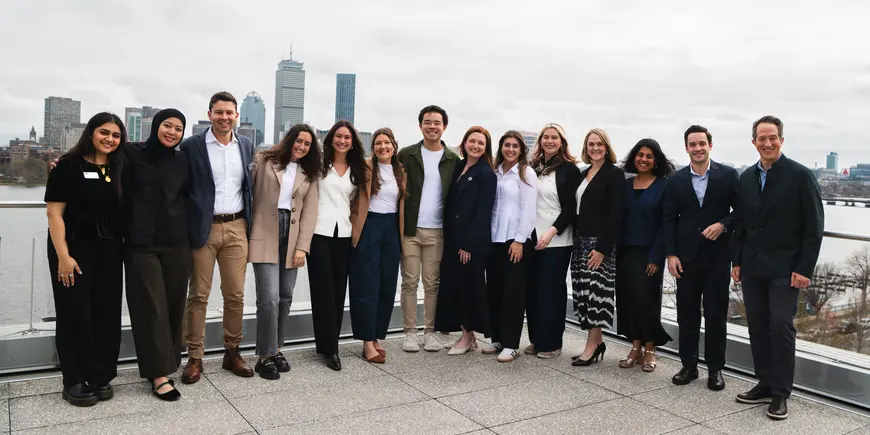 leadership team poses in group photo in front of Boston skyline