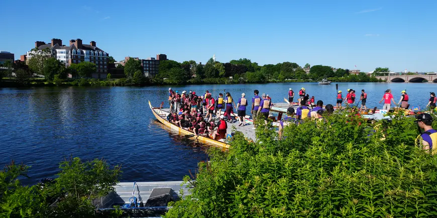 Group of people on river dock waits to board boats
