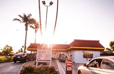 A fast food restaurant drive through lane, with palm trees in the background