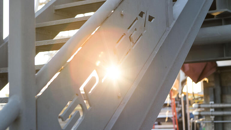 A railing with the sun shining through the SpaceX logo 