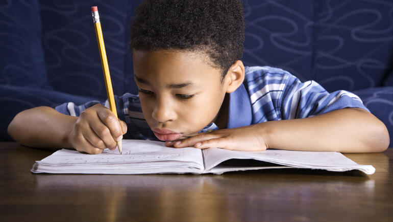 Child writing in book with a pencil