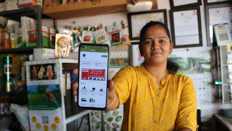 A retail shop owner demonstrates the Essmart mobile app on her smartphone.