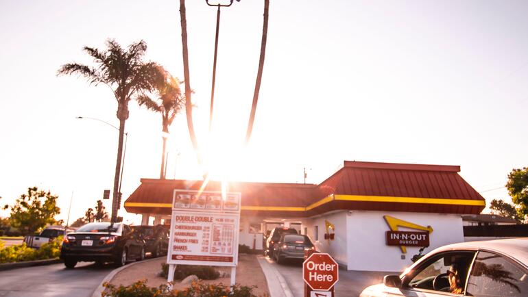 A fast food restaurant drive through lane, with palm trees in the background