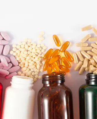 five brightly colored pill bottles on their sides with different sized pills spilling from each