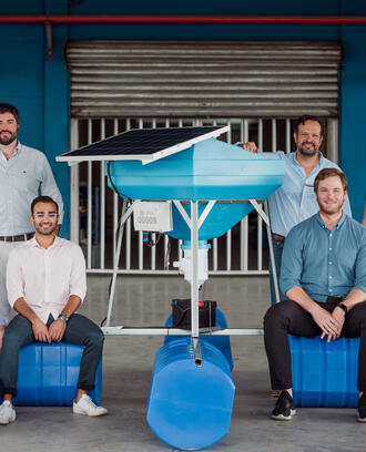 MIT Sloan students and bioFeeder co-founders posed around one of their shrimp-feeding systems.