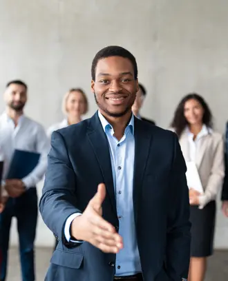 Business man extending his hand to you with a group of workers standing behind him