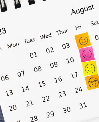 Happy face sticky notes cover the Friday column on a calendar