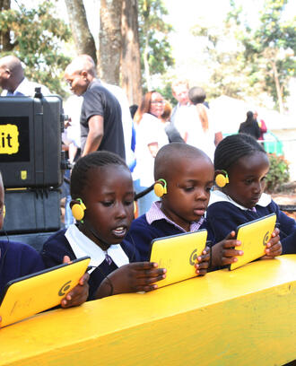 Children sitting in front of tablets smiling