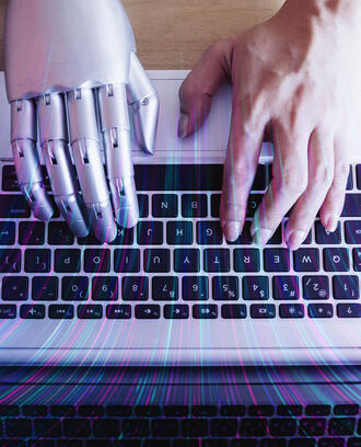 A robot hand and a human hand type on a keyboard
