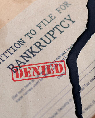 Petition to file for bankruptcy document torn in half with the stamp "denied" on it
