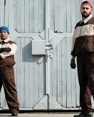 Image of two male workers standing in front of an industrial or warehouse-type building
