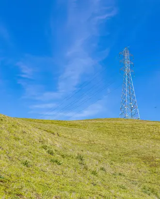 Image of an electrical tower on a hill with a blue sky background