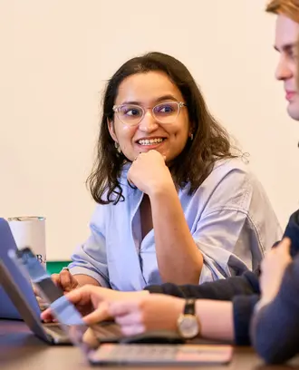 Kushi Pathak sits in front of a laptop, working with two other students