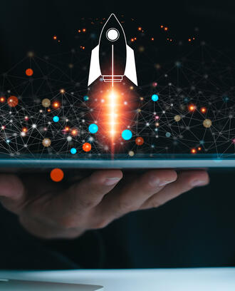 A business person uses a tablet is shown with a rocket symbol blasting off and shooting out of the screen with ai imagery