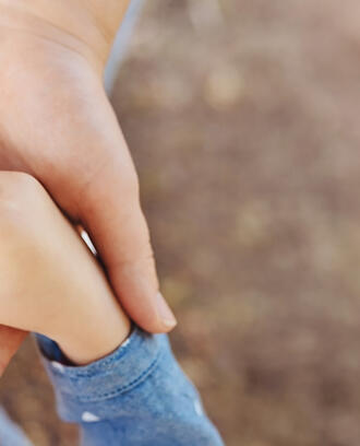 Adult hands holding child's hands in heart shape