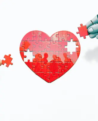 A robot hand and a human hand work on a heart puzzle with the silhouette of people inside
