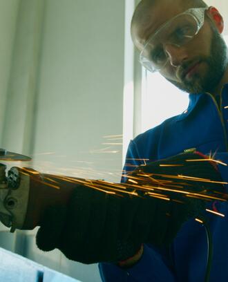 A worker in goggles is using a grinding machine