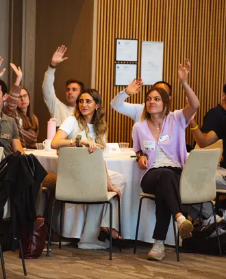 MIT MBA students raising their hands at an orientation program