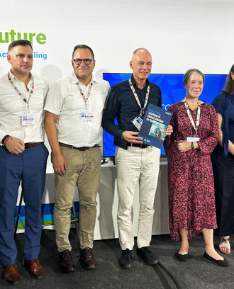 Event panelists, moderator, and organizers stand together.