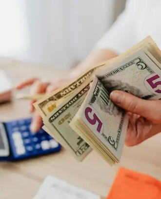 person holds cash and uses a calculator