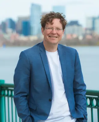 Headshot of a man outside in front of a river and skyline