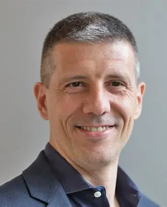 photo of a man with fair skin and gray hair wearing a navy blue shirt and jacket